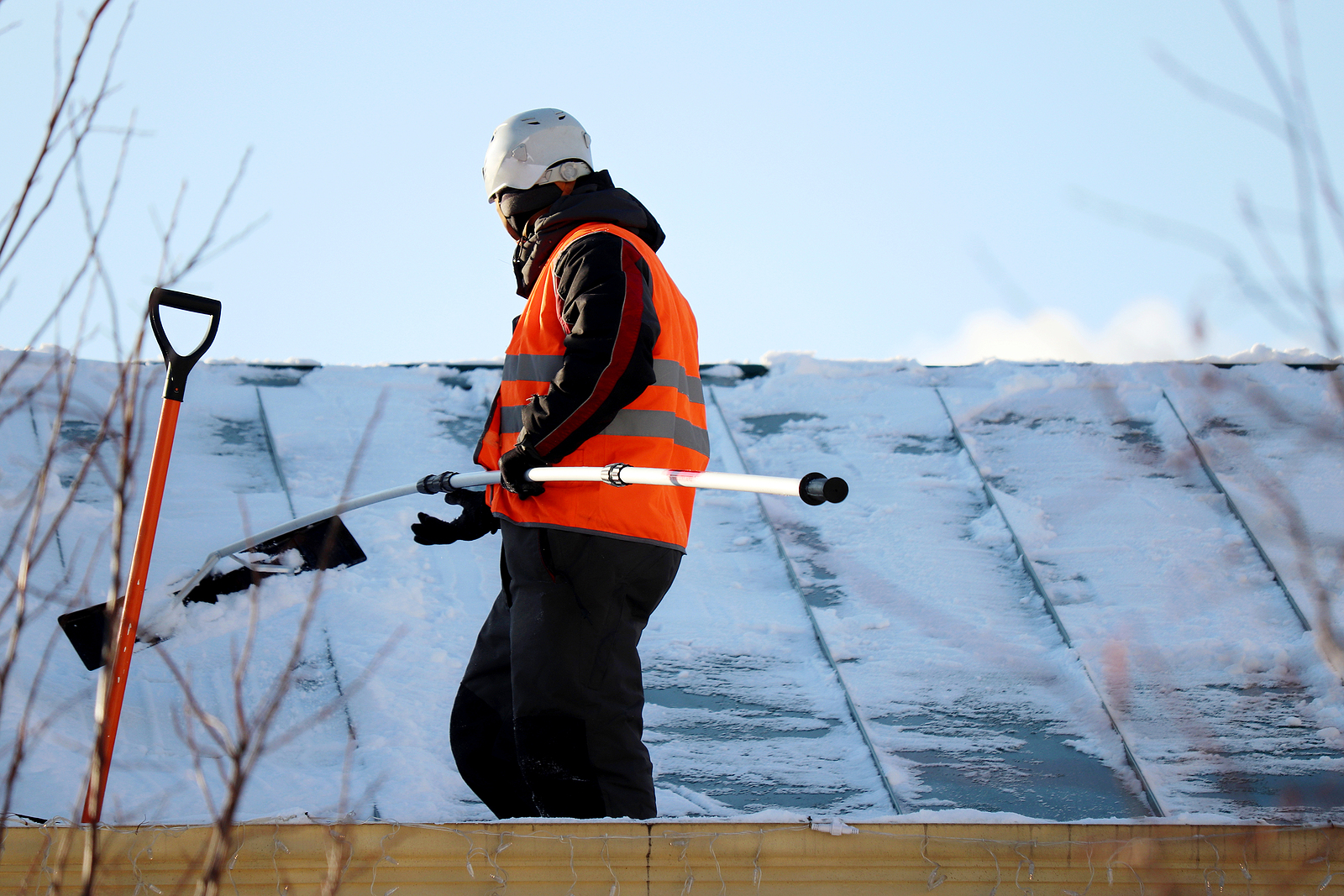 Worker Removing Snow On The Roof Of A Building. Snow Removal, Cl